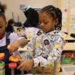 Two students in a classroom build blocks together